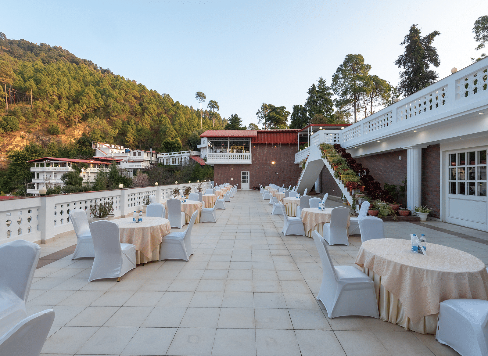 A spacious outdoor terrace with chairs at DLS Tehri Club Resort with stunning views of the surrounding mountains